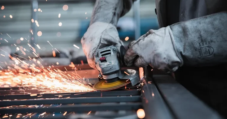 Grinding sparks off a rusted metal panel with a handheld power tool, similar abrasive action to a surface conditioning t
