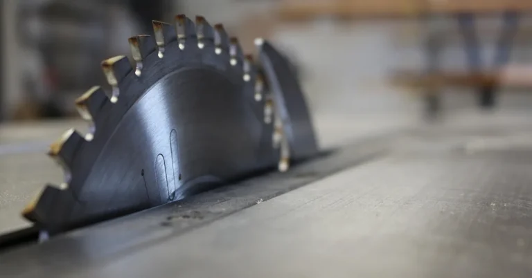 carbide-tipped table saw blade cutting through a dense hardwood board in a workshop