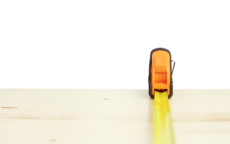 tape measure extended across a wood board checking actual lumber size