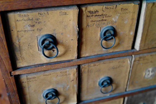 Finished wooden printer's tray mounted on a wall, filled with small collectible objects in each compartment