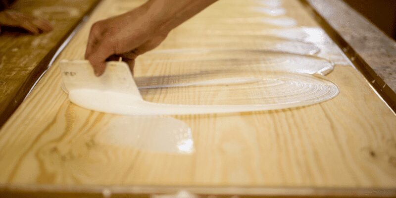 Adhesive being applied to the back of a rock before pressing it onto a wood surface Adhesive being applied to the back of a rock before pressing it onto a wood surface