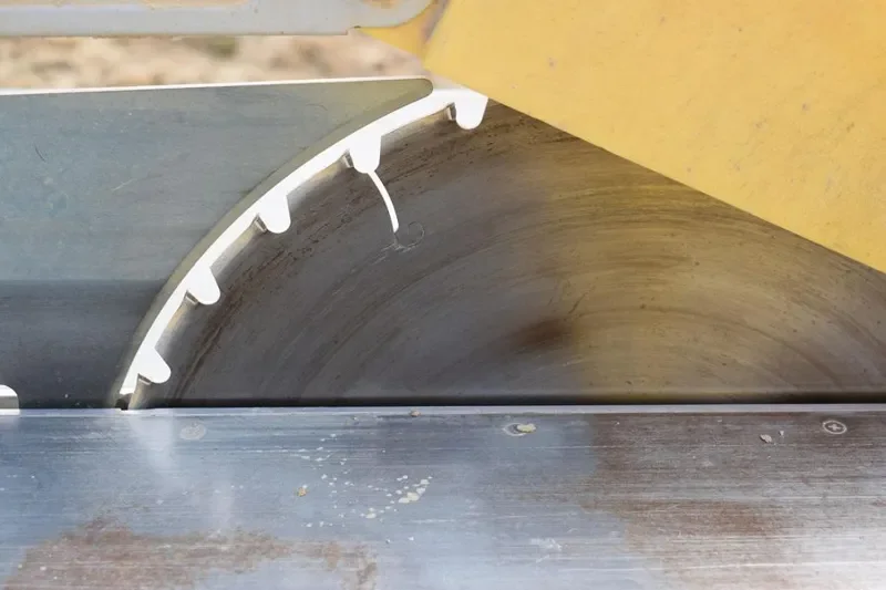 Table saw blade beside the aluminum rip fence