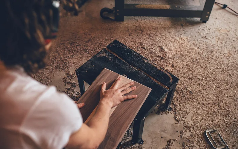 woodworker clamping a board on a workshop table surrounded by sawdust woodworker clamping a board on a workshop table surrounded by sawdust