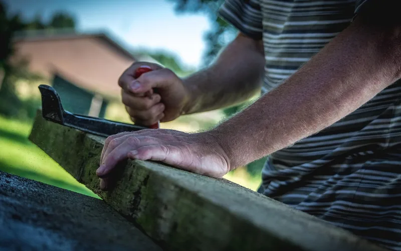 carpenter using a rip hand saw to cut through a wooden board outdoors carpenter using a rip hand saw to cut through a wooden board outdoors