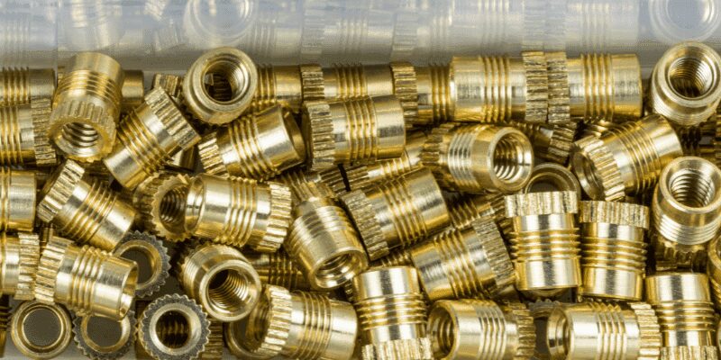 Close-up of a brass threaded insert installed flush in a hardwood workpiece
