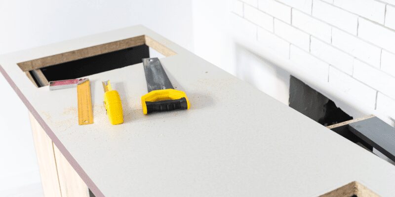marking tools laid out on a laminate countertop next to a finished cutout