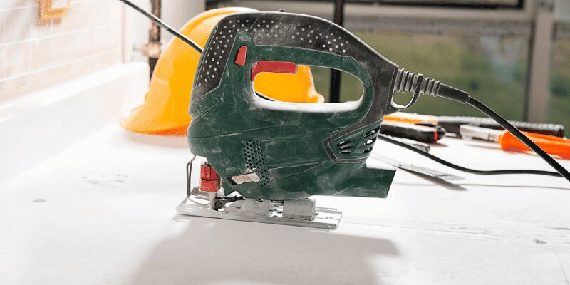 corded jigsaw and hard hat staged on a countertop before cutting a cutout