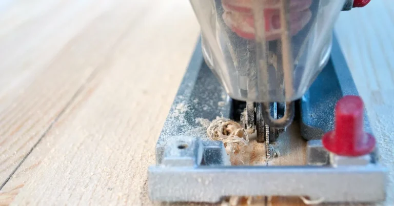jigsaw blade cutting into a wood board with sawdust curling off the edge