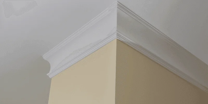White crown molding mitered at an outside wall corner where the wall meets the ceiling