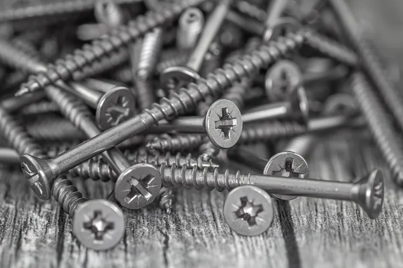 Close-up of stainless steel screws resting on weathered wood Close-up of stainless steel screws resting on weathered wood
