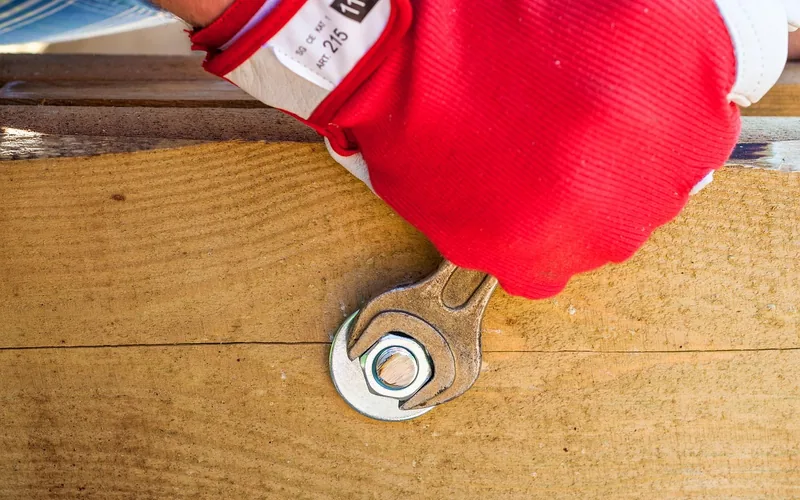 tightening a metal fastener into a wood beam during a maintenance check