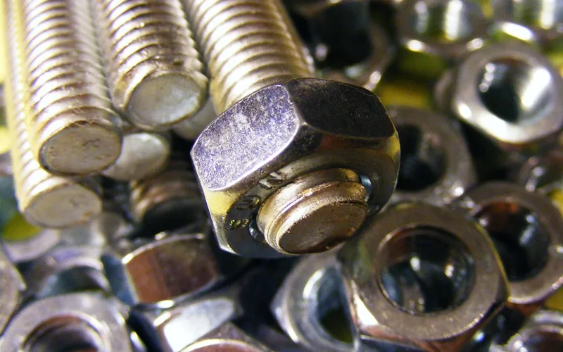 Close-up of steel through-bolts, washers, and nuts used to mount a bench vise