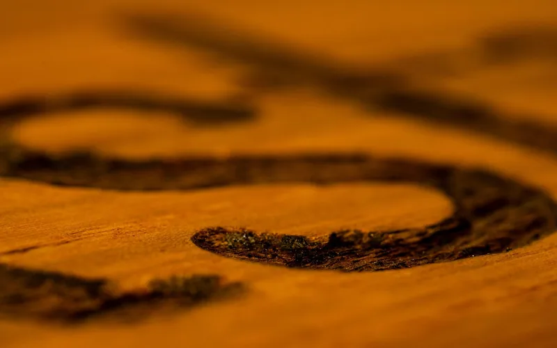 Wood burning pyrography pattern being burned into a wooden sword surface