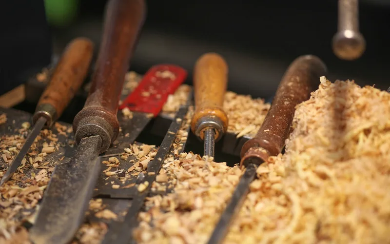 Wood carving gouges and chisels covered in shavings after shaping a sword blade