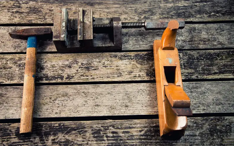 hammer, vise clamp, and wood hand plane on a workshop bench