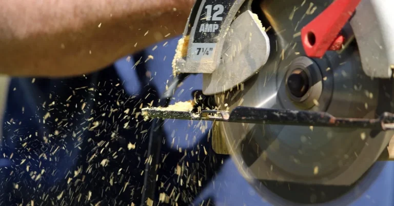 handheld circular saw blade cutting through a wood board with sawdust spraying