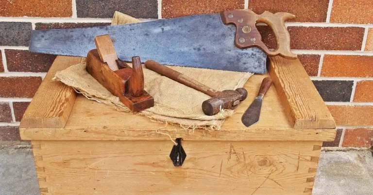 Traditional hand saw and antique woodworking hand tools on a wooden toolbox
