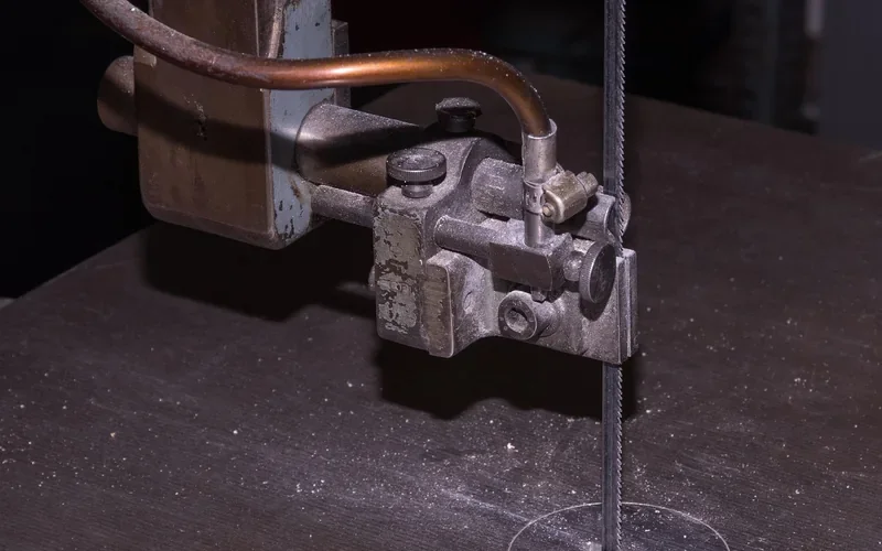 close-up of a band saw blade guide block assembly holding the blade above the table