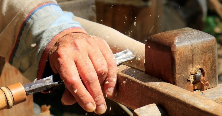 Woodworker turning a piece of wood on a lathe with chips flying