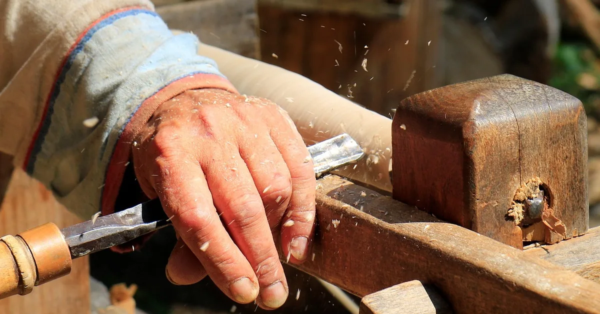 Woodworker turning a piece of wood on a lathe with chips flying