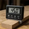Handheld digital protractor measuring the angle on the edge of a wood board