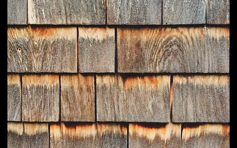 Weathered wood shingles with a grey surface layer and fresher orange-brown wood showing