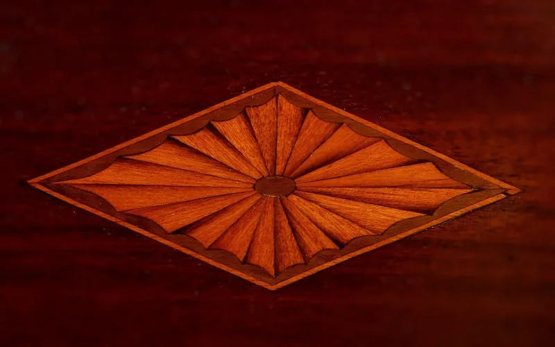 Detailed wood marquetry inlay medallion, the kind of fine fretwork a fret saw is used to cut