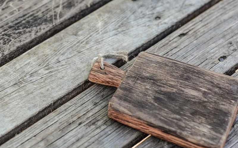 Small wooden cutting board with a rope loop resting on weathered planks