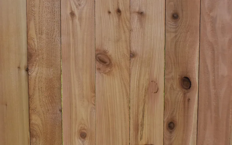 Knotty cedar-toned fence boards with warm reddish grain