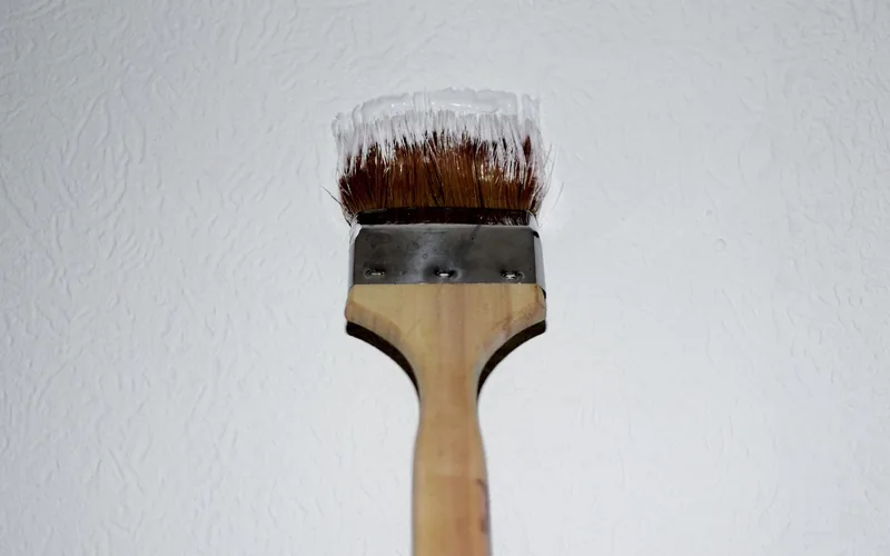 Paint brush loaded with white primer coating a textured wall Paint brush loaded with white primer coating a textured wall