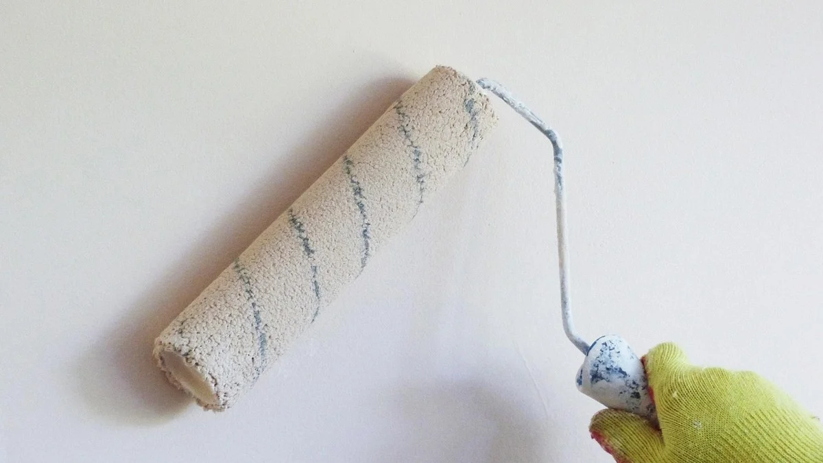 Paint roller applying white primer to an interior wall