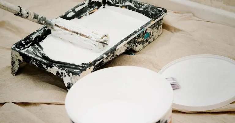 Paint can, roller tray, and loaded roller set up for a primer coat on drop cloth