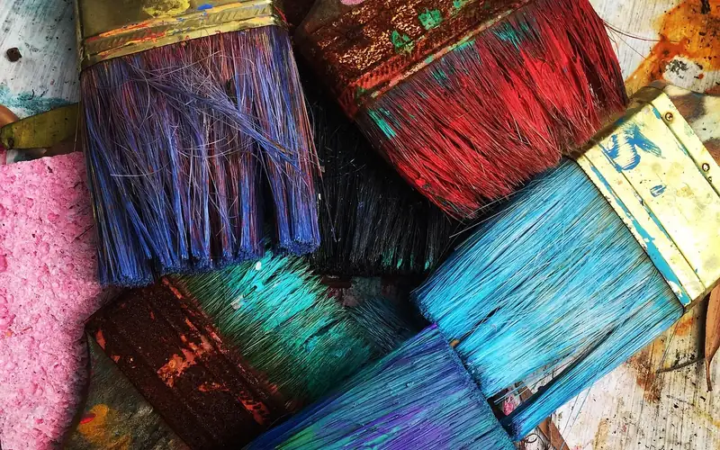 colorful paintbrushes loaded with acrylic pigment on a work table