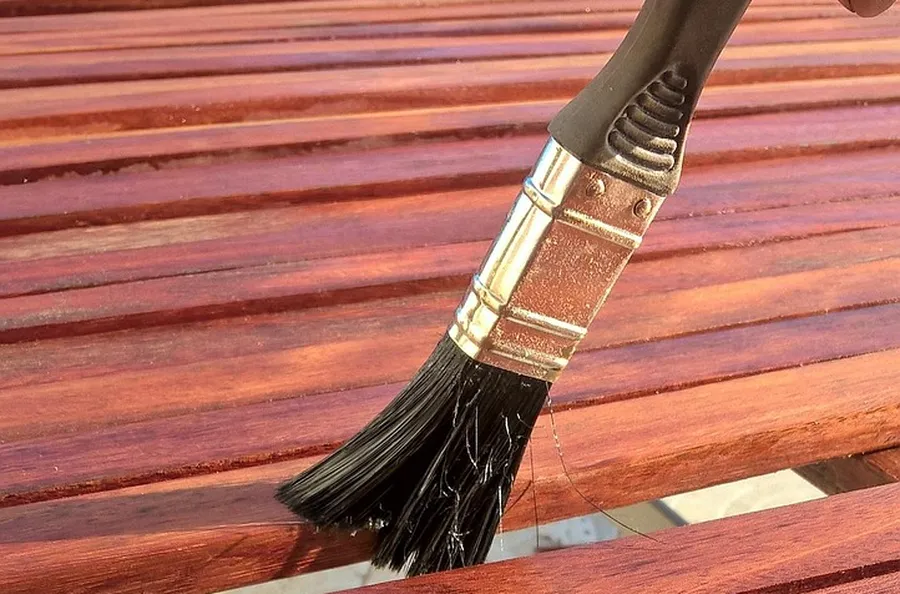 Brushing a coat of wood preservative onto outdoor wood slats