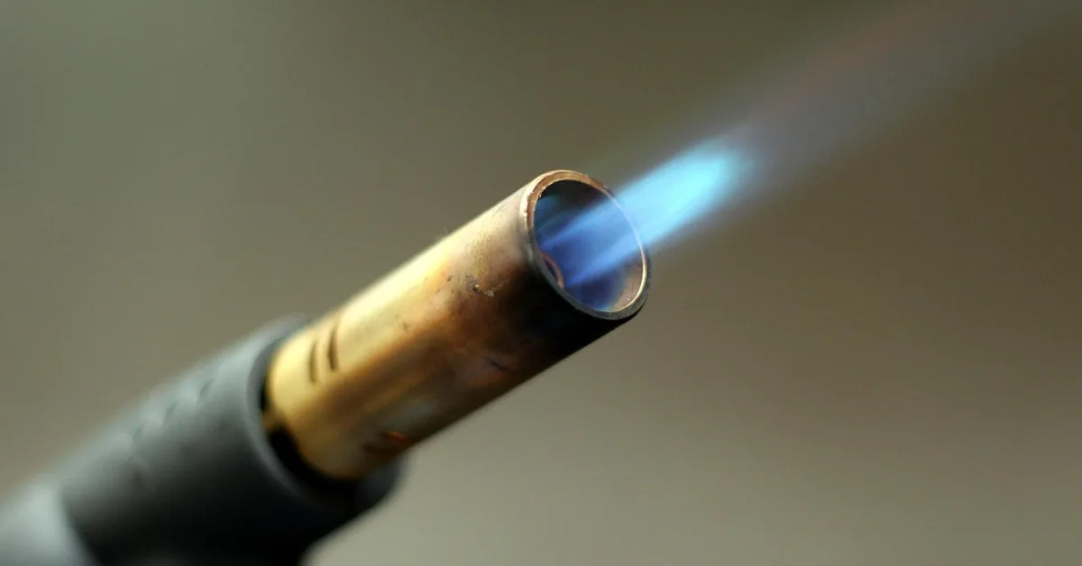 butane micro torch nozzle producing a precise blue flame used for wood burning