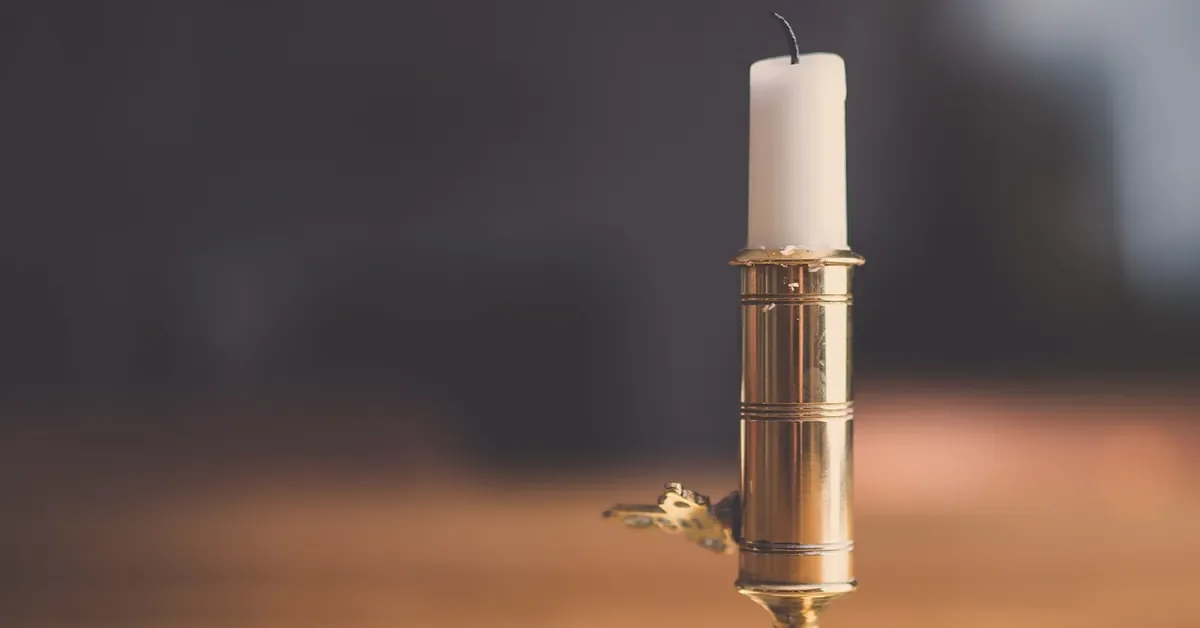 Candle in a brass holder on a wooden table