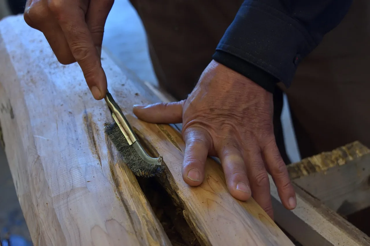 Brushing debris out of a cut slot in a wood board before finishing