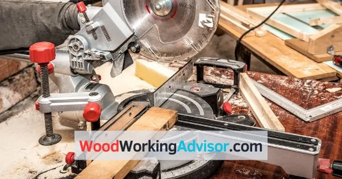 Compound miter saw clamped to a workbench mid-cut through a wood board