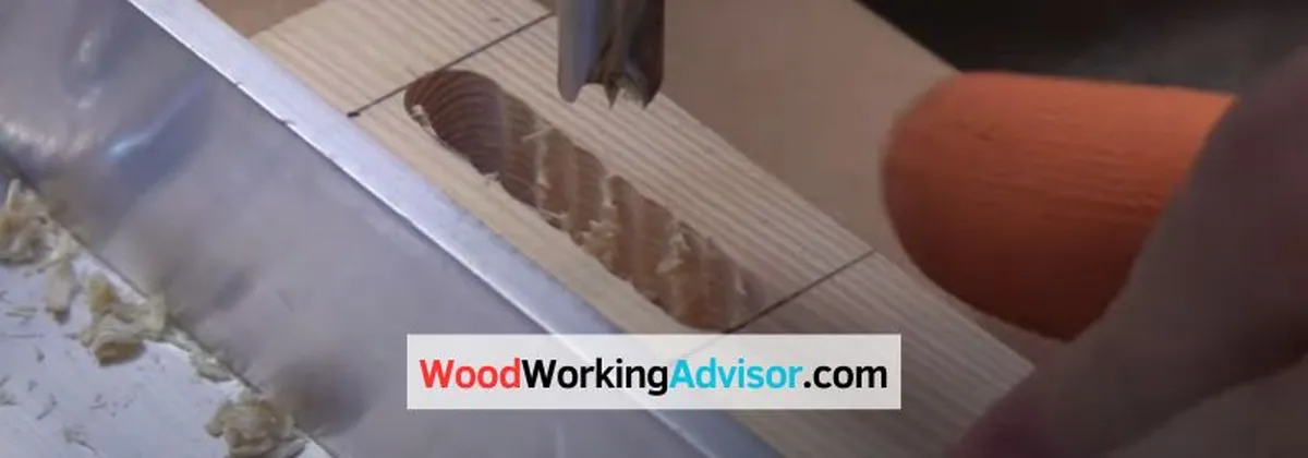 Drill bit cutting a slotted hole into a wood board