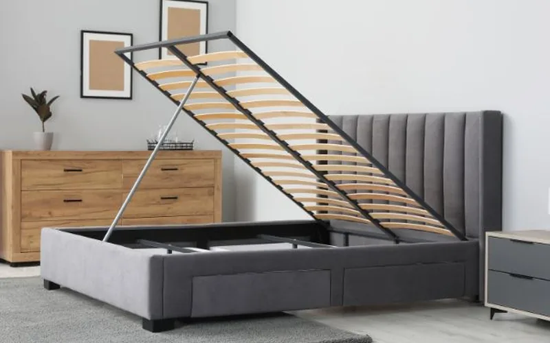 upholstered bed frame lifted open showing wooden slats and metal support frame underneath