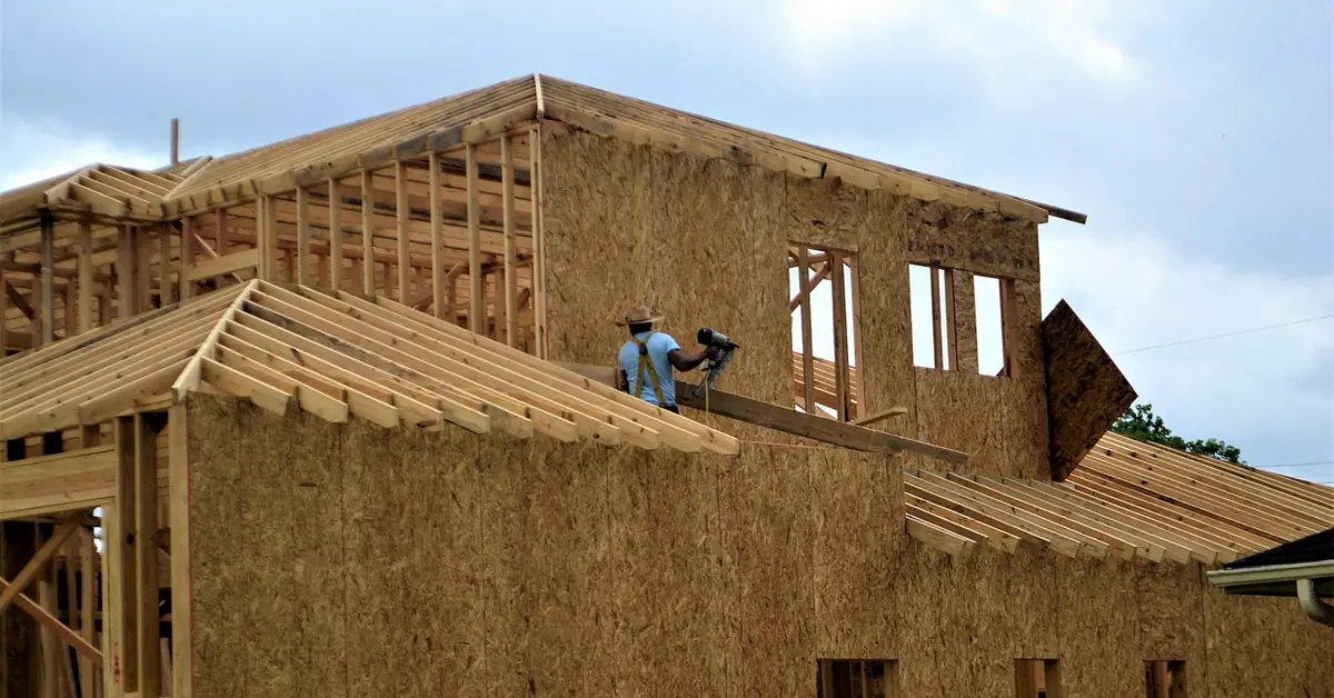 contractor using a pneumatic nail gun to fasten wood structural panel sheathing to a wall frame