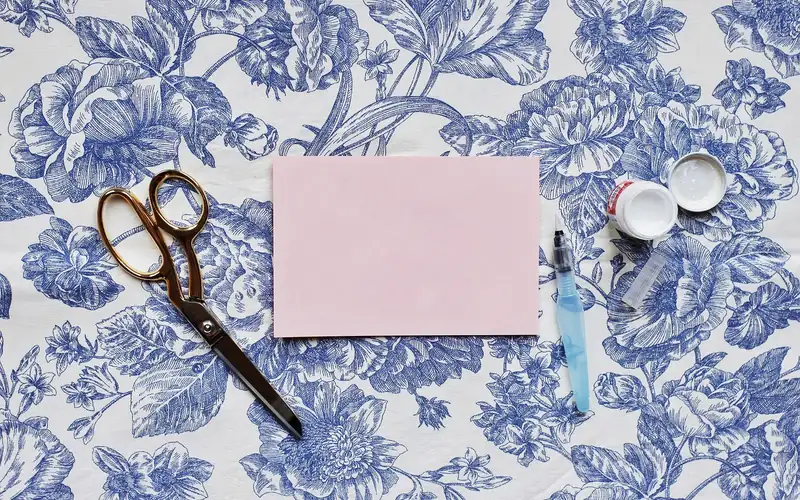 Paper craft glue and scissors Craft glue pot with scissors and pink paper set up for a paper craft project