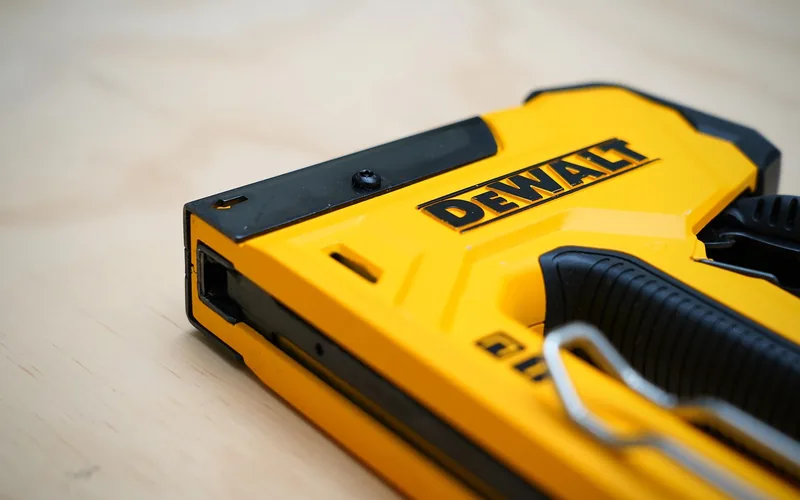 pneumatic nail gun driving nails into wood structural panel