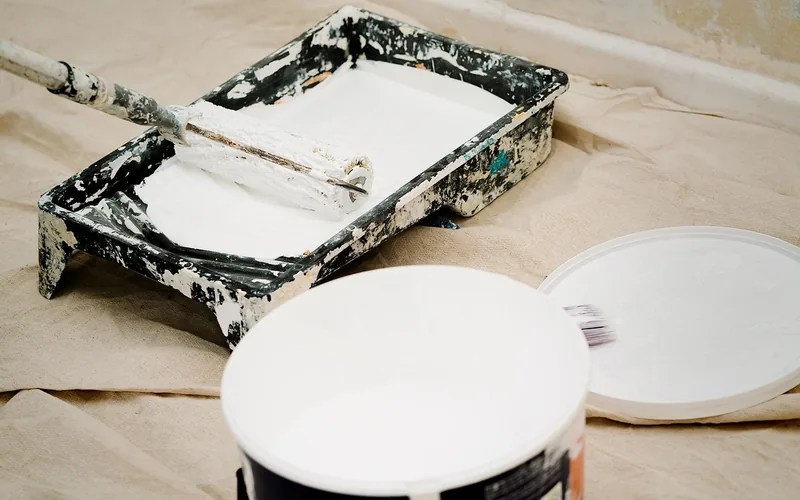 white primer in a paint tray with roller and open paint can on a drop cloth white primer in a paint tray with roller and open paint can on a drop cloth