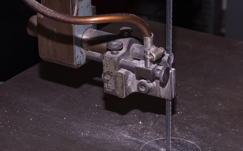 close-up of a woodworking bandsaw blade and guide assembly on a wood-shop bandsaw table