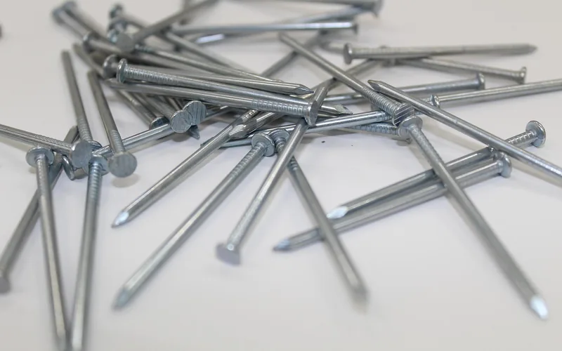 Pile of loose steel finish nails on a white surface showing shank diameter Pile of loose steel finish nails on a white surface showing shank diameter
