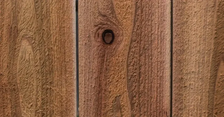 Rough-sawn cedar fence boards with a warm reddish-brown finish and a visible knot