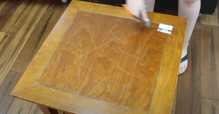 Hand applying oil and vinegar solution with a cloth to a scratched wooden coffee table