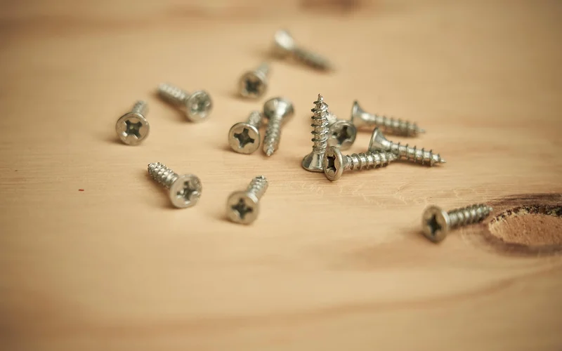 Short wood screws scattered on a plank, the type used for squeaky floor repair Short wood screws scattered on a plank, the type used for squeaky floor repair