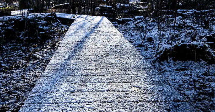 Frost and light snow covering wooden boardwalk planks in winter
